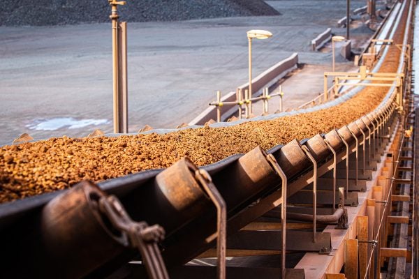 Conveyor belt transporting wet sticky ore in mining operation illustrating anti-clogging challenges.